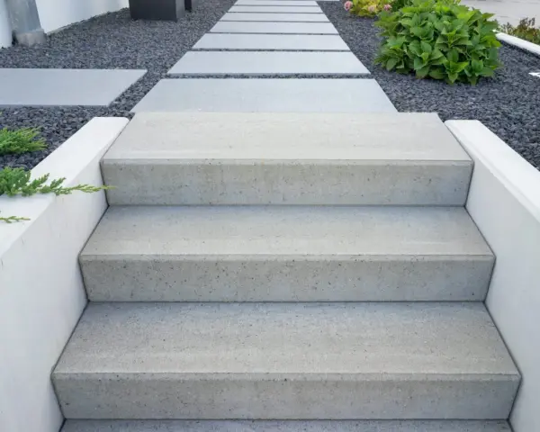 Nowe schody do ogrodu zrób sam. Nowoczesne, betonowe stopnie prowadzą przez kamienny żwirek do zieleni.
