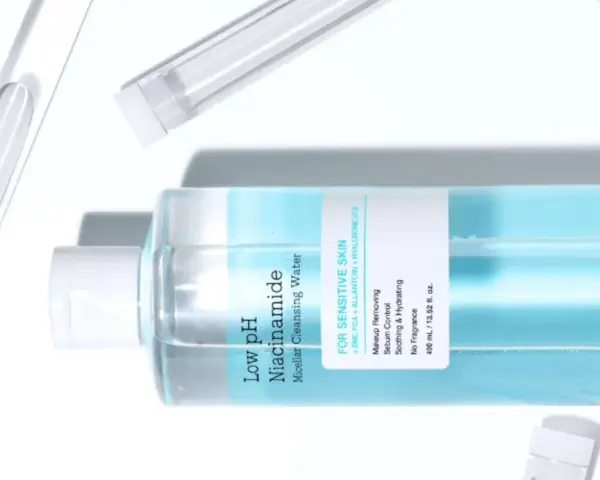 En flaska COSRX Low pH Niacinamide Micellar Cleansing Water, en mild sminkborttagning olja för känslig hud, omgiven av provrör.