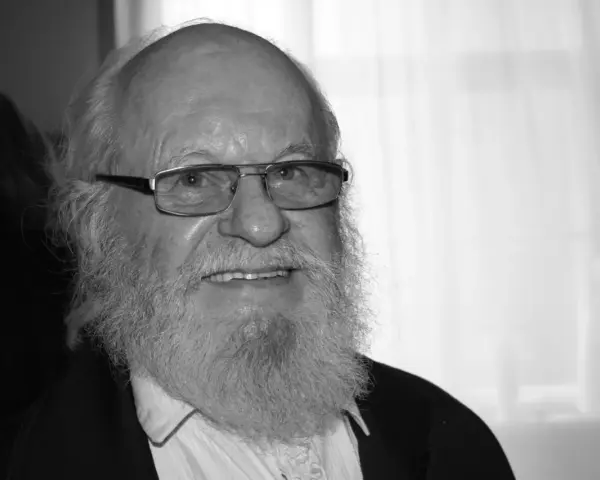 Uśmiechnięty Aleksander Skowroński z siwą brodą i okularami.