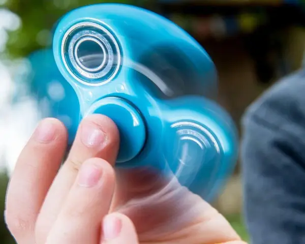 En blå finger spinner snurrar snabbt i handen, med suddiga kanter som visar rörelsen.