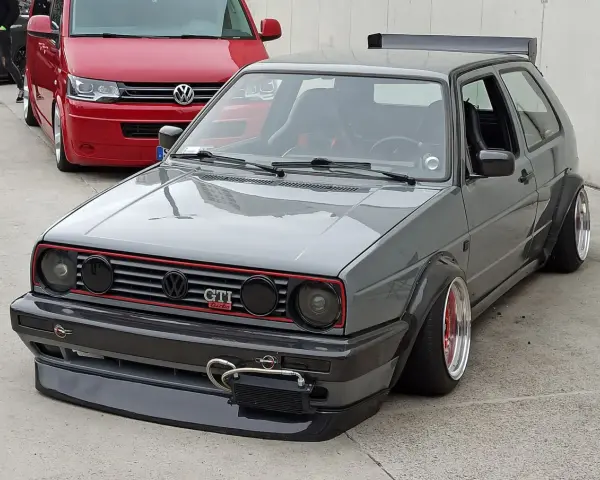 Szary, zmodyfikowany Volkswagen Golf GTI z szerokimi błotnikami i spojlerem.