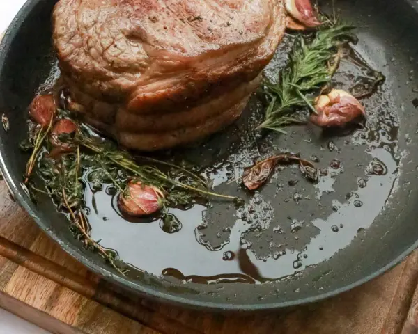 Rouelle de porc au barbecue, rôtie dans une poêle avec de l'ail et des herbes aromatiques, prête à être dégustée.