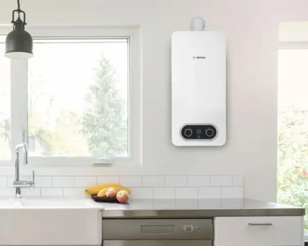 Scaldabagno a gas Bosch bianco, con pannello di controllo digitale, montato a parete in una cucina moderna.