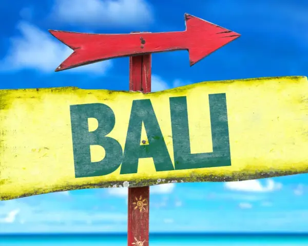 Strzałka kierunkowa wskazuje drogę do Bali. W tle błękitne niebo i morze.