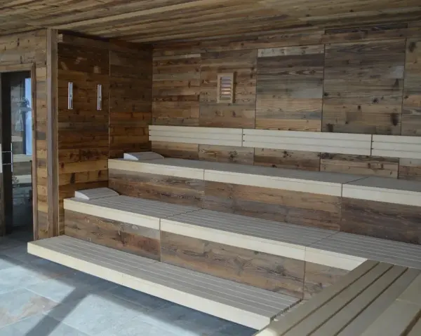 Drewniana sauna w domu z wielopoziomowymi ławami i kamienną podłogą. Idealne miejsce na relaks.