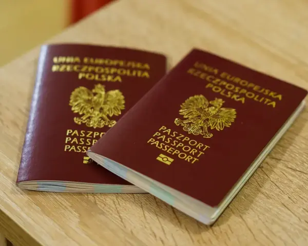 Dwa polskie paszporty leżące na drewnianym blacie.