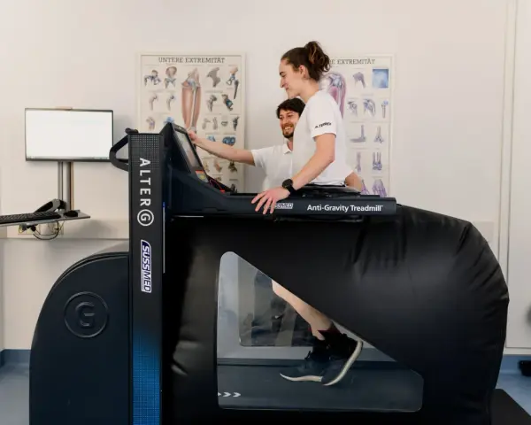 Donna in gravidanza usa un tapis roulant anti-gravità con un fisioterapista.