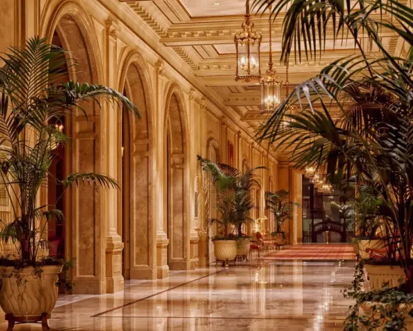 Elegancki korytarz z łukami i palmami, przypominający wnętrze najdroższego hotelu na świecie.