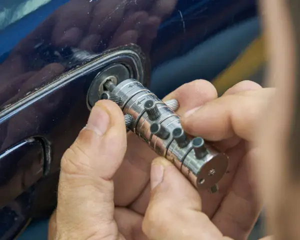 Specjalista manipuluje zamkiem, by otworzyć auto. Dowiedz się, ile kosztuje awaryjne otwieranie samochodu.
