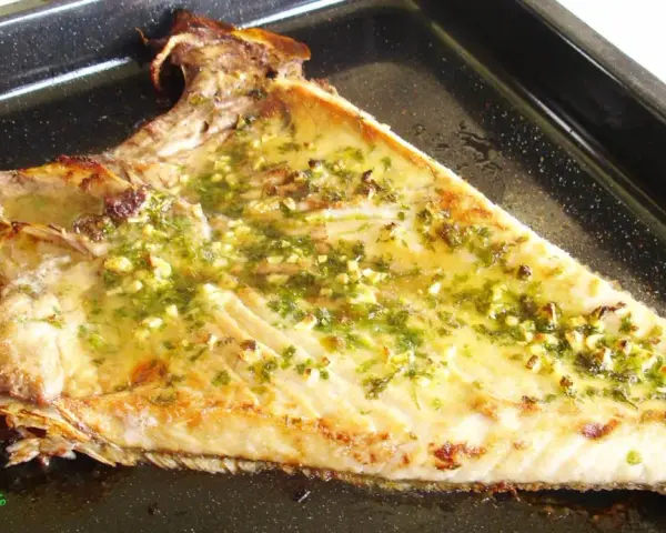 Deliciosa ventresca al horno, dorada y jugosa, con un aderezo de ajo y perejil que invita a probarla.