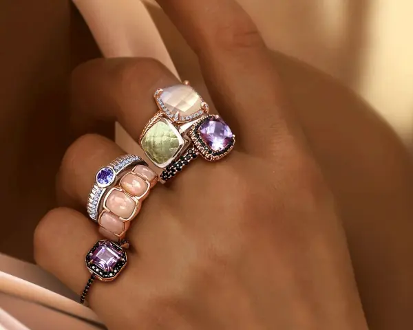 Dita adornate con anelli che esaltano il loro fascino, un vero **materiale prezioso** che cattura la luce.
