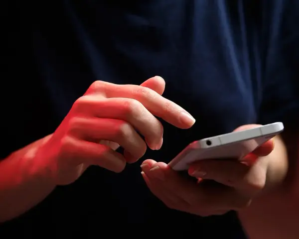 Dłonie z czerwonym podświetleniem obsługują smartfon, być może ustawiając **direct debit** na rachunki.