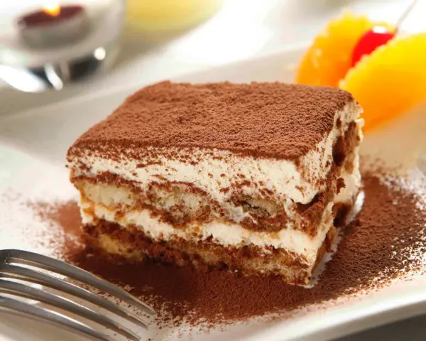 Pyszne tiramisu Ani Starmach, posypane kakao, z owocami i wisienką. Idealne na deser.
