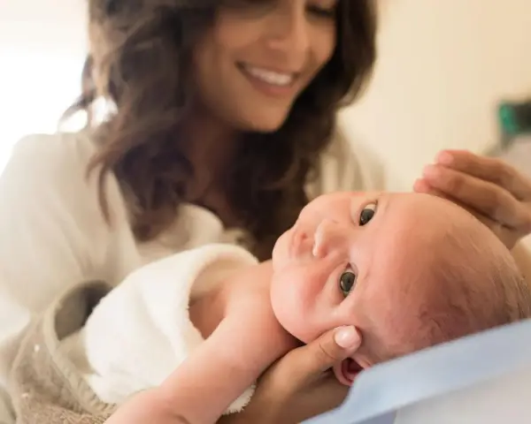 Lächelnde Mutter hält ihr Baby, das gerade einen Wachstumsschub durchmacht.
