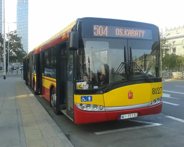 Autobus 504 OS.KABATY z numerem bocznym 8127 stoi na przystanku. W tle widać nowoczesne budynki.