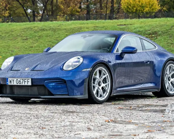 Niebieskie Porsche 911 na mokrej nawierzchni. Zastanawiasz się nad porsche 911 cena? Ten model zachwyca.