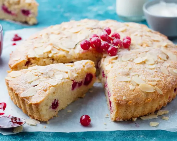 Saftiger zitronenkuchen ohne mehl, mit roten Johannisbeeren und Mandelblättchen bestreut. Ein Genuss!