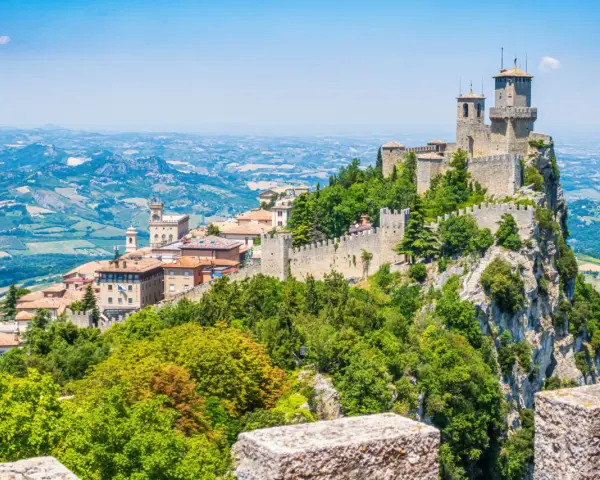 Trzy wieże obronne górują nad malowniczym krajobrazem San Marino, otoczone zielenią i historyczną zabudową.