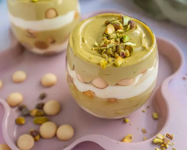 Pyszny deser w pucharku: krem pistacjowy z mascarpone, przełożony biszkoptami i posypany pistacjami.