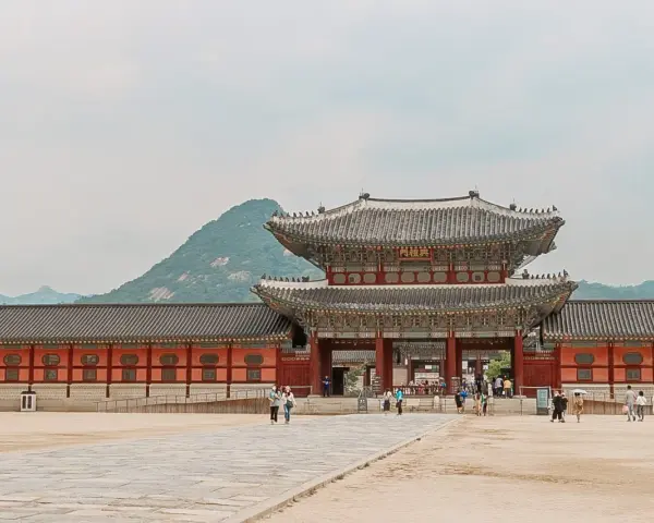 Zwiedzający pałac w Seulu, podziwiający architekturę. Czy Korea Południowa jest bezpieczna? Tak, to kraj przyjazny turystom.