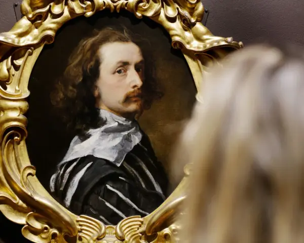 Portret mężczyzny w złotej ramie, jedno z dzieł Antoona van Dycka, oglądany przez widza.