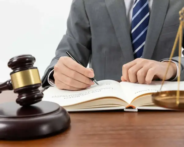 Un juez con toga y corbata escribe en un libro. A su lado, un mazo y la balanza de la justicia. ¿Cuánto cobra un juez en España?