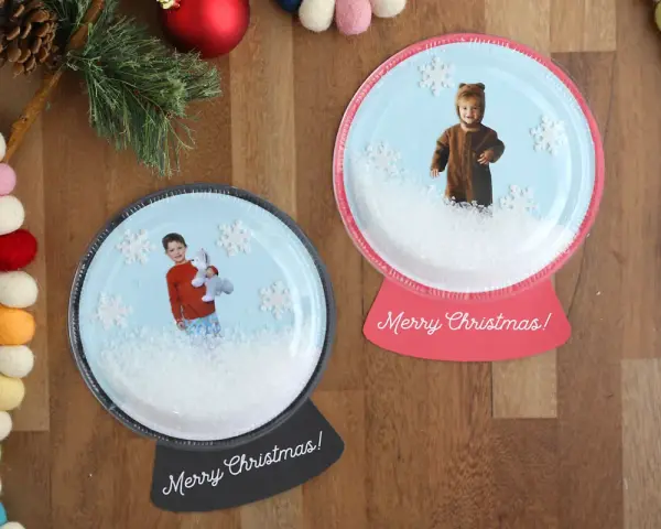 Dwie personalizowane kule śnieżne ze zdjęciami dzieci i płatkami śniegu.