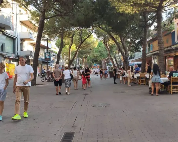 Passeggiata serale nel riccione centro storico, tra negozi e ristoranti all'aperto sotto gli alberi.