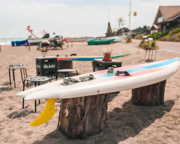 Windsurfbrett am Strand, ein echter Dahme Geheimtipp für Wassersportler. Gelbe Finne ragt aus dem Sand.