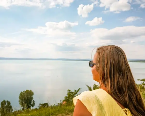 Kobieta w okularach przeciwsłonecznych podziwia rozległe jezioro Balaton.