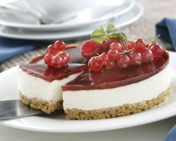 Tarta de queso Philadelphia con frutos rojos y gelatina de fresa, lista para servir.