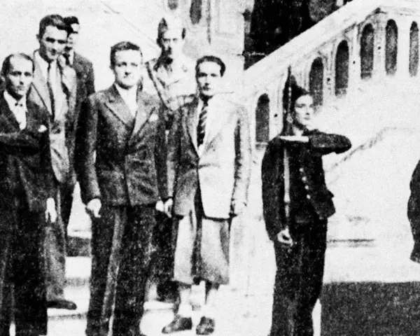 Groupe d'hommes en costume, dont Henri Frenay et François Mitterrand, posant devant un escalier.