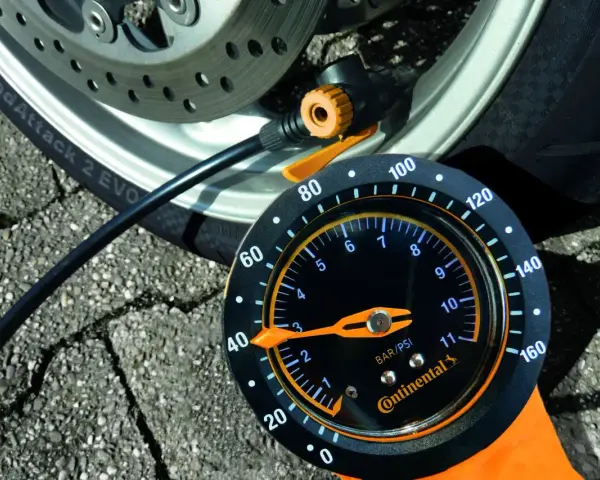 Manometro Continental per pneumatici moto, collegato alla ruota. La lancetta indica la pressione.