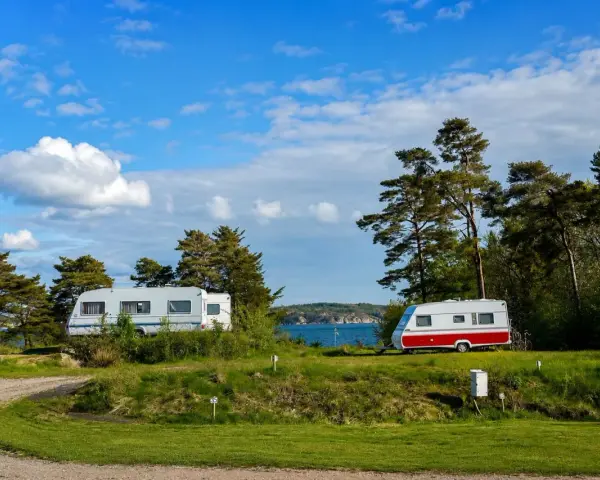 Två husvagnar på en grönskande campingplats vid havet i Lysekil. Blå himmel med vita moln.
