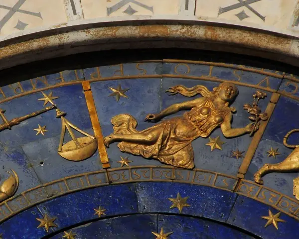 Złota Wenus, pana znak zodiaku, trzyma kwiaty na tle niebieskiej tarczy z gwiazdami i wagą.