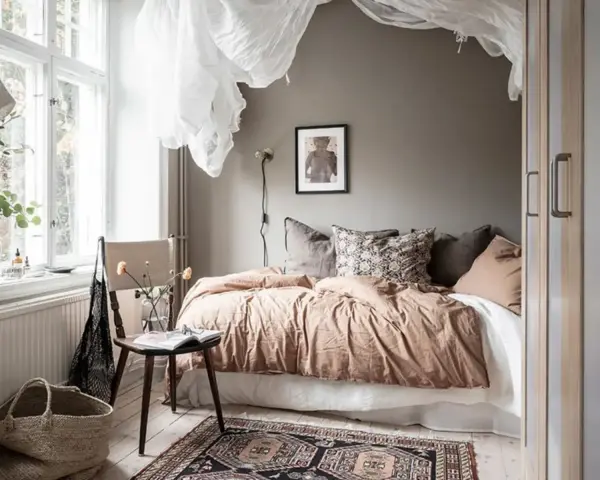 Camera da letto in **stile nordico**, con letto accogliente, tessuti naturali e un tappeto decorativo. L'ambiente evoca un **stile norvegese** rilassante.