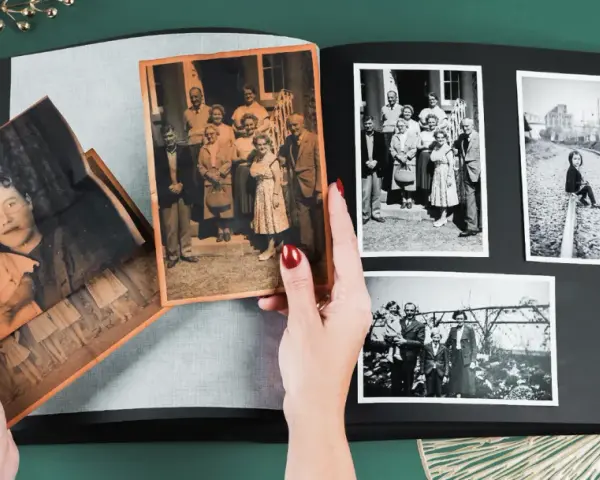 Ręce układają stare fotografie w albumie, pokazując, jak skanować zdjęcia i zachować wspomnienia.