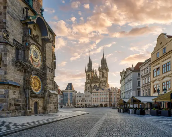 Praga co zobaczyć w jeden dzień: Ratusz Staromiejski z zegarem astronomicznym i Kościół Marii Panny przed wieżami w blasku porannego słońca.