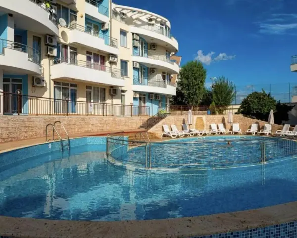 Słoneczna plaża w Bułgarii: basen z leżakami i hotel w tle, idealne miejsce na wakacje.
