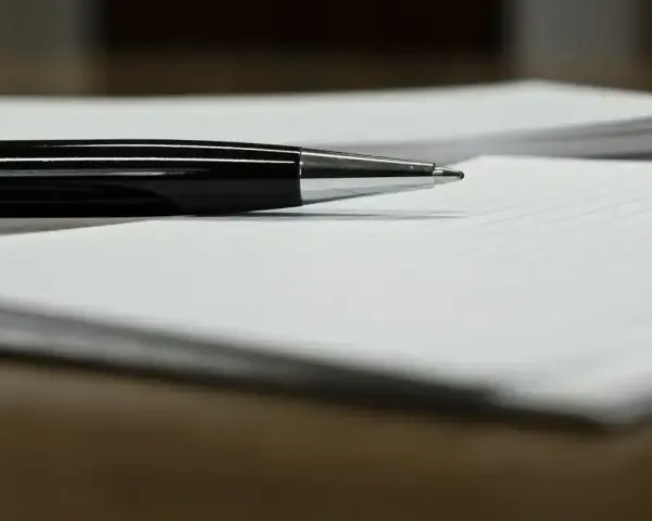 Czarny długopis leży na papierze, gotowy do podpisania ważnego dokumentu, np. pełnomocnictwa.