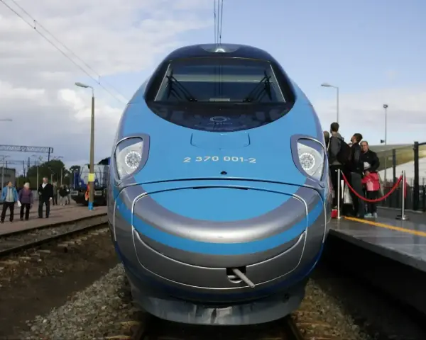 Pendolino Kraków Gdańsk cena: nowoczesny pociąg na torach, pasażerowie czekają na peronie.