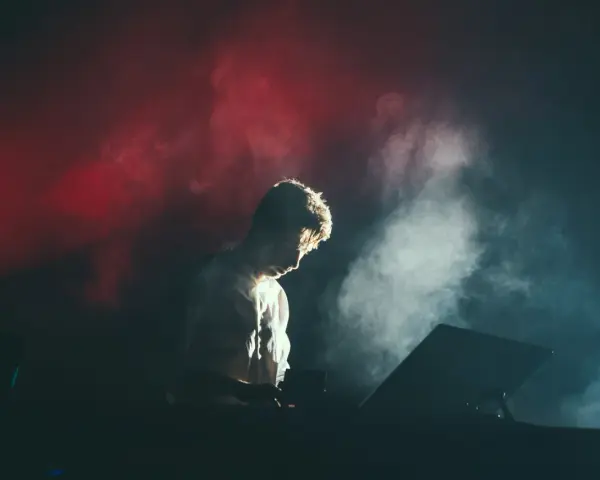 Un DJ dans la fumée rouge et blanche, plongé dans sa musique. Combien de temps avant le traumatisme sonore ?