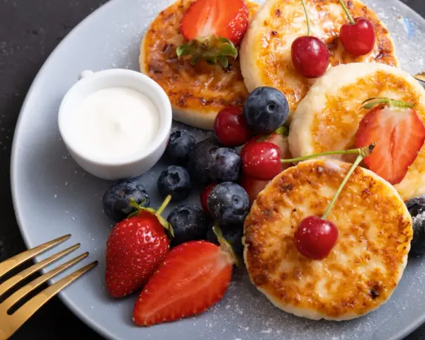 Pyszne placuszki z twarogu, idealne na śniadanie z airfryer, podane z owocami i śmietaną.