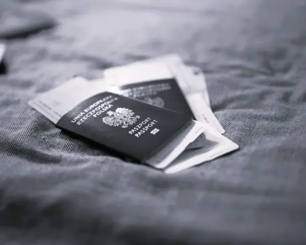 Polskie paszporty leżą na tkaninie, symbolizując długi pobyt w Polsce i plany na pobyt za granicą.