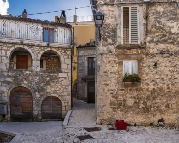 Antico borgo in pietra, con archi e balcone in ferro battuto. La **pretoro altitudine** offre scorci suggestivi tra vicoli acciottolati e case antiche.