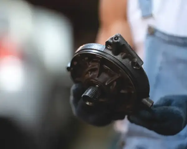 Mechanik trzyma element serwa hamulcowego. Objawy awarii mogą być różne, np. twardy pedał hamulca.