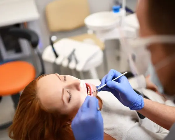 Pacjentka z rudymi włosami u dentysty. Badanie jamy ustnej, które może być związane z diagnostyką twardziny układowej.