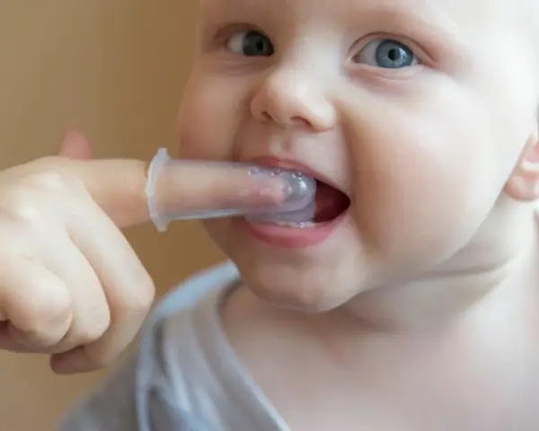 Malutkie ząbki mleczne dziecka są delikatnie czyszczone palcem w silikonowej nakładce.