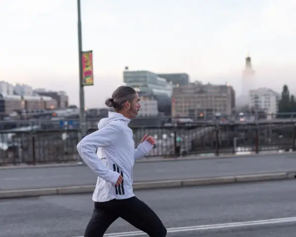 Man med hästsvans springer på en bro i Stockholm, klädd i adidas halvmarathon-kläder.