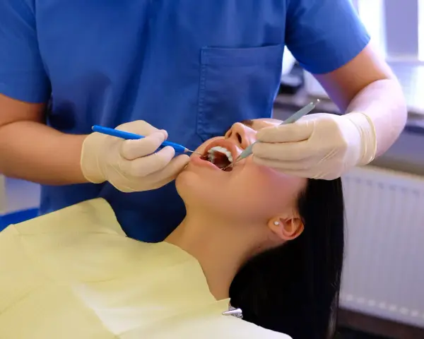 Dentysta wykonuje fluoryzację zębów pacjentki, dbając o ich zdrowie i ochronę przed próchnicą.